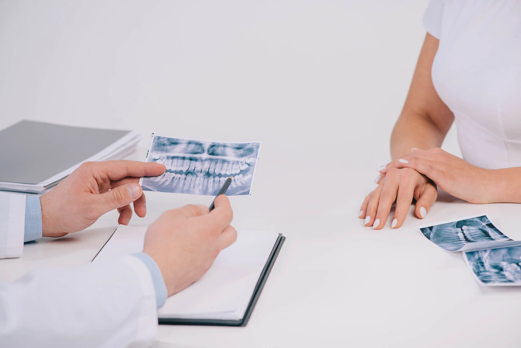 Dental provider shows X-ray results to patient while seated at a white table