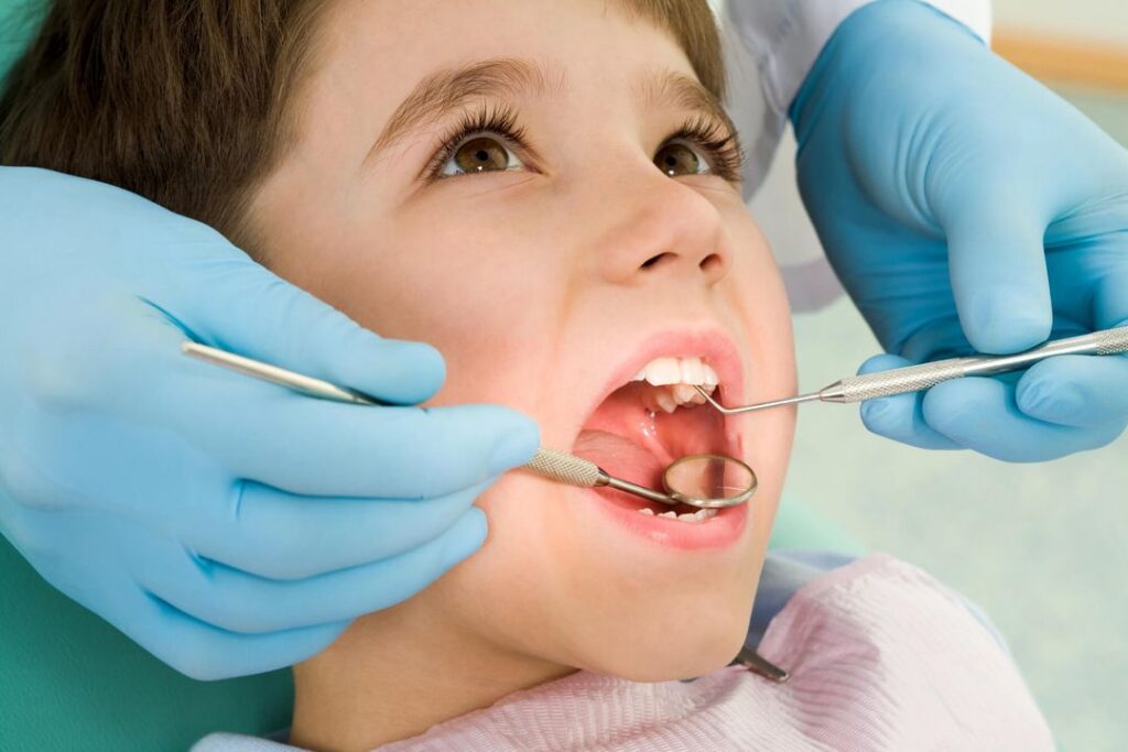 Orthodontist wearing blue gloves checks on young boy's teeth during office visit
