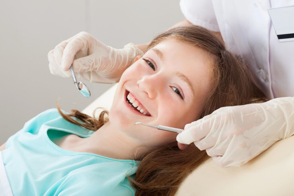 Young girl smiles to camera during orthodontist checkup