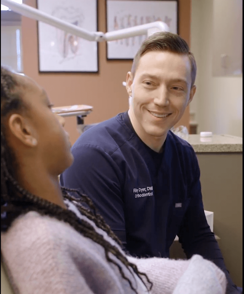 Dr. Dyer smiles talking to teen patient during orthodontic visit